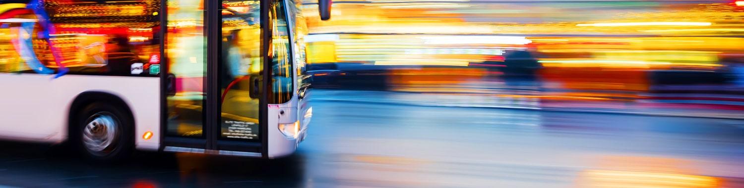 Ein Elite Niederflur Linienbus fährt durch die Stadt bei Abend