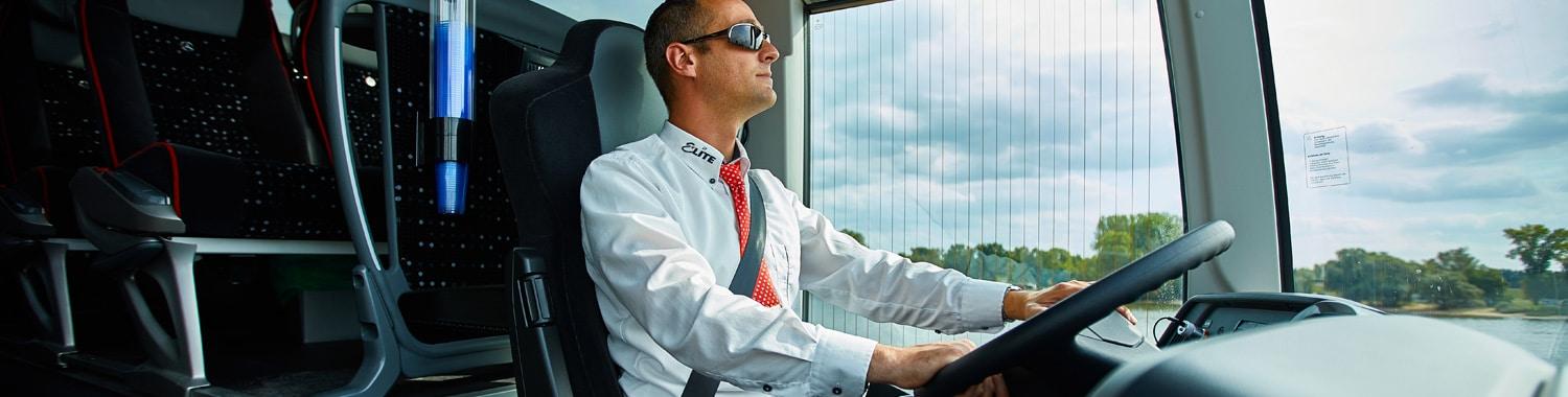 Ein freundlicher Busfahrer fährt einen Reisebus von EliteBus